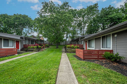 A row of studio and one bedroom apartments at The Retreat at Indian Lake with green lawns and trees in the background.
