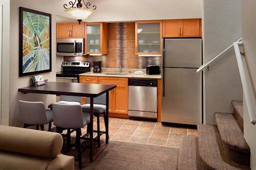 A kitchen with a refrigerator, stove, and sink at Fusion Buckhead.