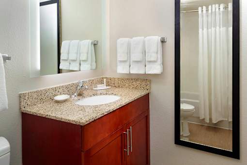 A bathroom with a counter, sink, mirror, toilet, and towels at Fusion Buckhead Apartments.