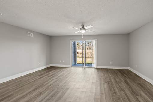 A living room with a ceiling fan and sliding glass doors at Mandarin Bay Apartments.