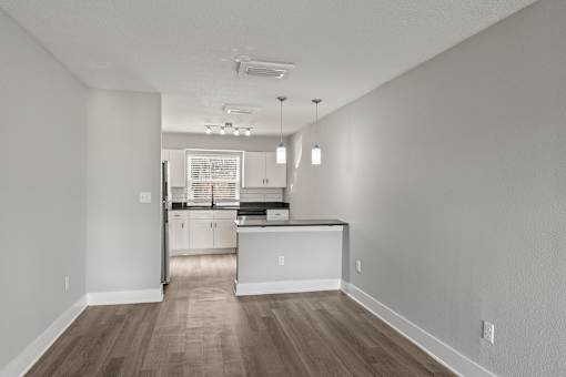 A kitchen with white cabinets and a wooden floor at Mandarin Bay Apartments.