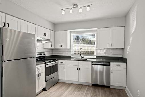 A kitchen with white cabinets and a stainless steel refrigerator at Mandarin Bay Apartments.