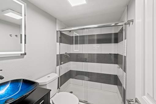 A bathroom with a toilet, sink, and shower at Mandarin Bay Apartments.