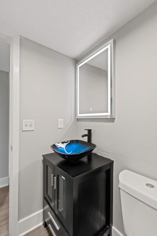A bathroom with a black cabinet and a white toilet at Mandarin Bay Apartments.