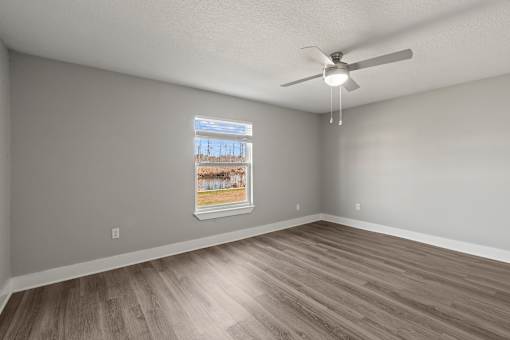A bedroom with a ceiling fan and a window showing a view of a body of water at Mandarin Bay Apartments.
