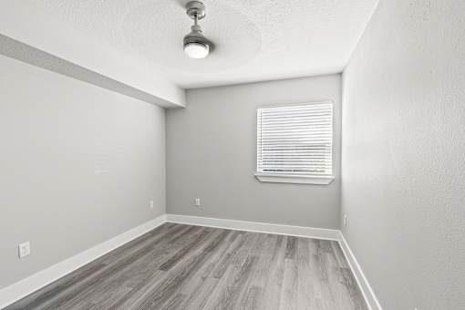 A room with a window and wooden flooring.