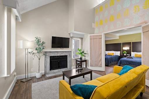 A living room with a yellow couch and a fireplace.