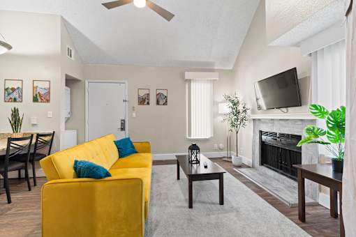 A living room with a yellow sofa and a fireplace at Fusion Orlando furnished apartments.
