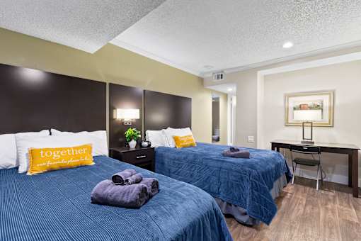 Two beds with blue bedspreads and yellow pillows in a bedroom at Fusion Orlando.
