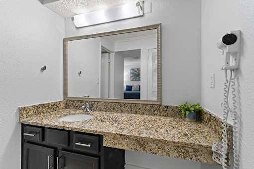 A bathroom with a granite countertop and a large mirror.