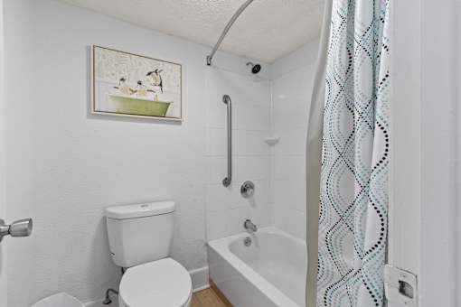 A white toilet sits next to a white bathtub in a bathroom.