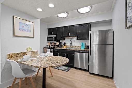 A kitchen with a granite table and a refrigerator.