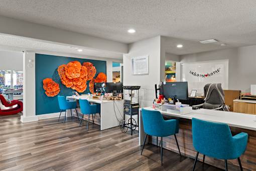 A room with a desk and chairs and a flower on the wall at the Fusion Orlando apartments leasing office