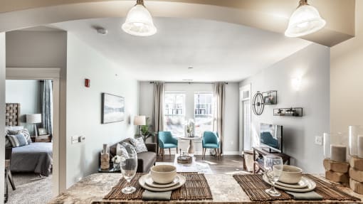A dining room table set for two, across from a furnished living room at the Fort.