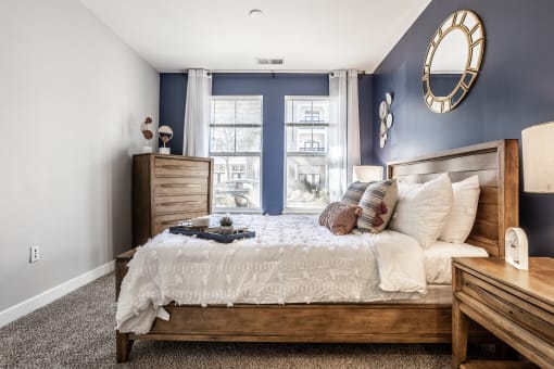 A bedroom at The Fort with a bed, two wooden dressers, and carpeted flooring.
