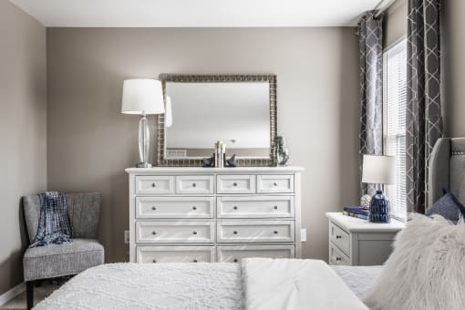 a bedroom with a large white dresser with a mirror on top of it