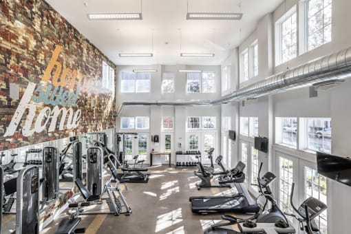Fitness center with a selection of workout machines and weights, surrounded by large windows.