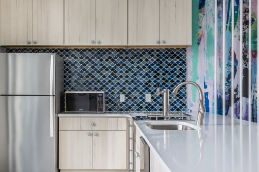 a kitchen with white cabinets and a blue and white tiled backsplash
