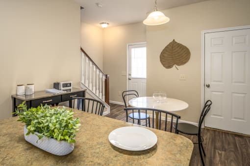 Apartments for Rent in Pickerington, OH - Arbors at Turnberry - Dining Room with Small Table and Two Chairs, a Coffee Bar, and Stairs in the Background.