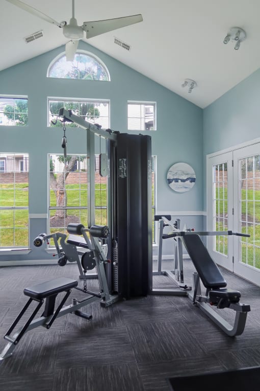 Apartment community gym with various exercise equipment and natural light from large windows