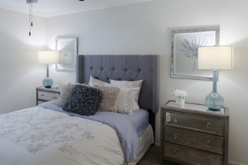 Stylish bedroom with plush carpet, ceiling fan, and vaulted ceiling in a one-bedroom apartment at The Boulevard