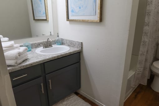 Bright bathroom featuring a mirror, sink, and toilet with neutral finishes
