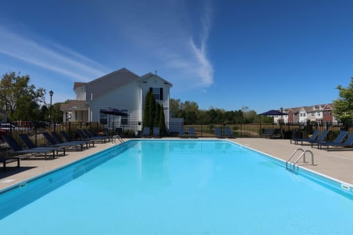 a swimming pool with chairs and a building in the background