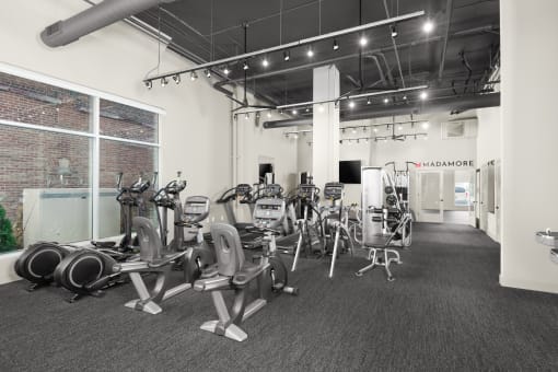 a large fitness room with cardio equipment and a large window