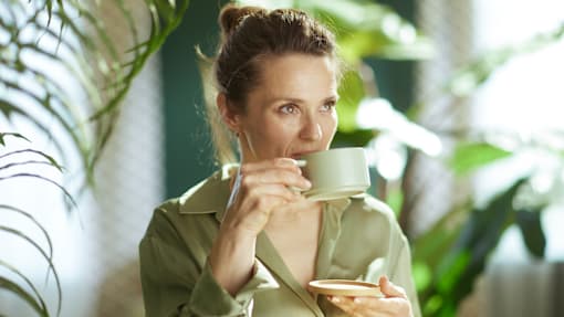 A woman is drinking from a green mug.
