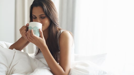 A woman is drinking from a blue and white mug.