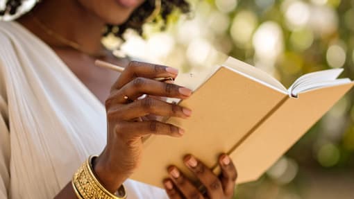 A woman is reading a book outdoors.