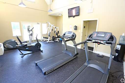 A gym with treadmills, elliptical machines, and other exercise equipment.