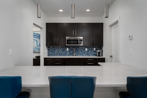 a kitchen with a large island with a white counter top and blue chairs