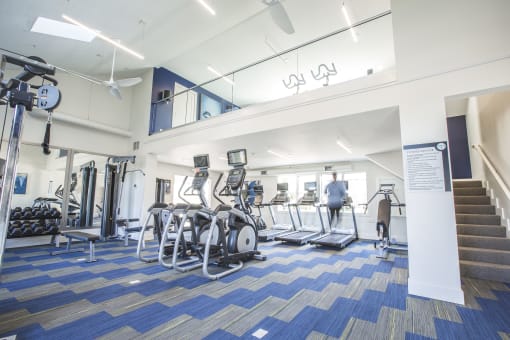 a view of the gym with cardio equipment and a staircase in the background