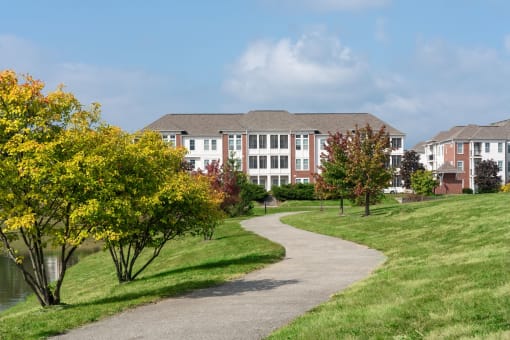 Exterior view of The Fort with a walkway surrounded by grass and tall trees.