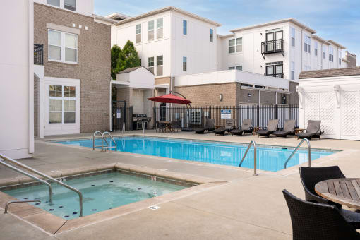The Fort swimming pool with chairs and a red umbrella, and a black fence.
