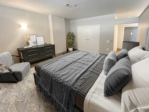 A bedroom with a large bed and a chair.