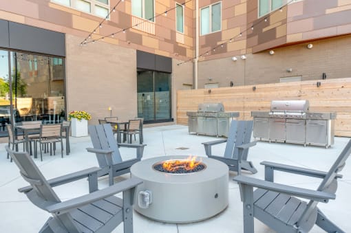 a fire pit in the middle of a patio with chairs and tables