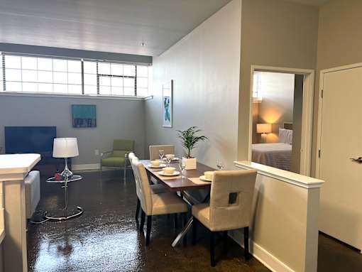 A dining room with a table set for two and a potted plant.