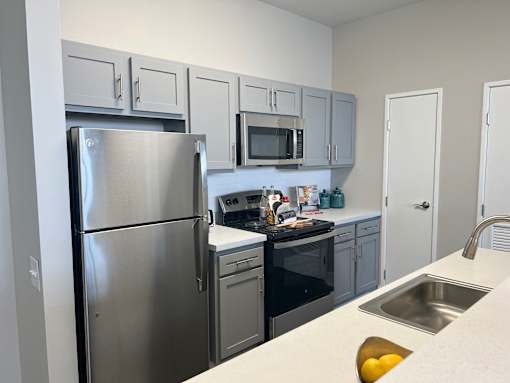 A modern kitchen with a stainless steel refrigerator, microwave, and oven.