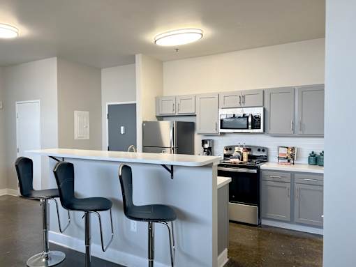 A kitchen with white cabinets and black bar stools.