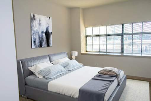 A bedroom with a large bed and a painting on the wall.