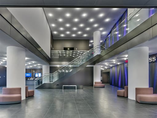the lobby of a large building with a staircase and chairs