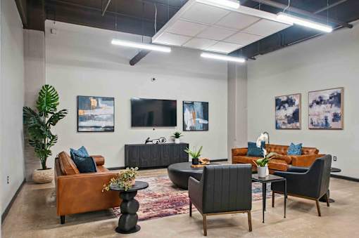A modern living room with a brown leather couch, a black armchair, and a wooden coffee table.