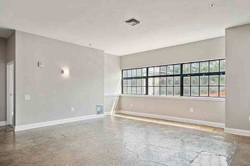 A large empty room with a window and a door.