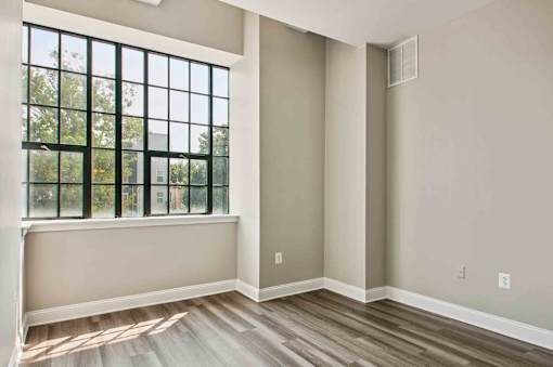A room with a large window and wooden flooring.