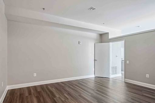 A room with a white door and a brown floor.