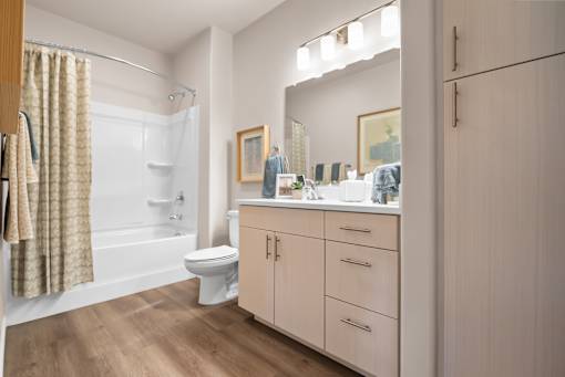 A bathroom with a toilet, sink, and cabinets.
