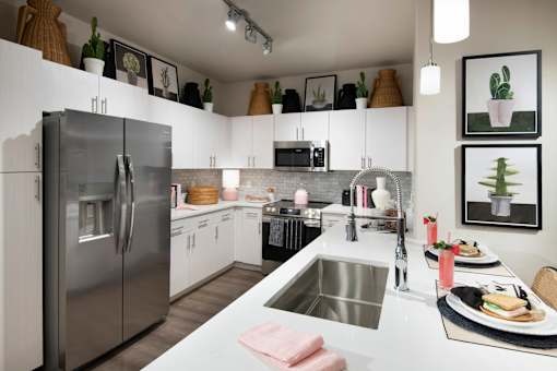 A modern kitchen with a stainless steel refrigerator and a dining table set for two.
