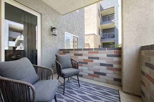 Two chairs are on a patio with a brick wall.